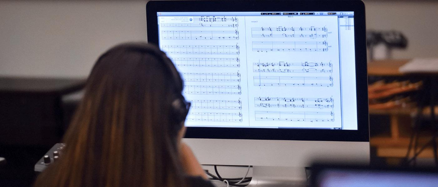 female student sitting in front of computer looking a music notes